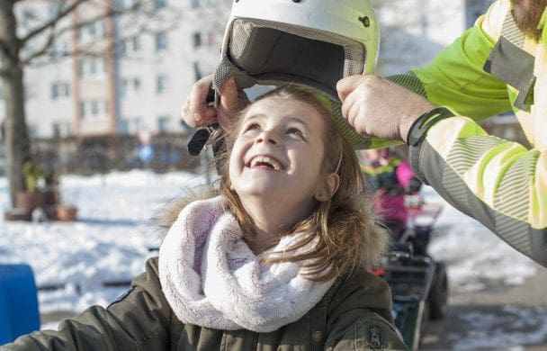 Glückliches Mädchen auf Quad mit Helm im Winter