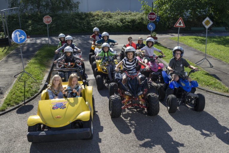 Kiddi-Car Kinderverkehrstraining Kiddi-Car Club 5 Kinder auf Verkehrsübungsplatz warten auf grüne Ampel